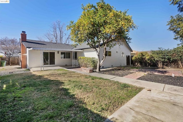 back of property with a yard and a patio area