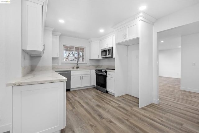 kitchen featuring sink, light hardwood / wood-style flooring, appliances with stainless steel finishes, light stone counters, and white cabinets