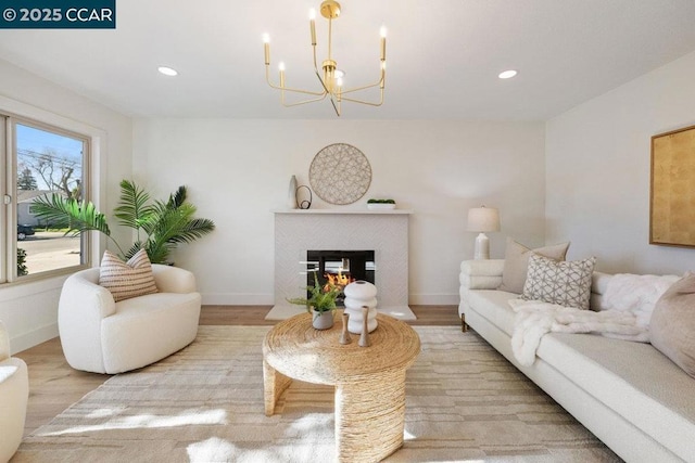 living room featuring light wood-type flooring, a notable chandelier, and a multi sided fireplace