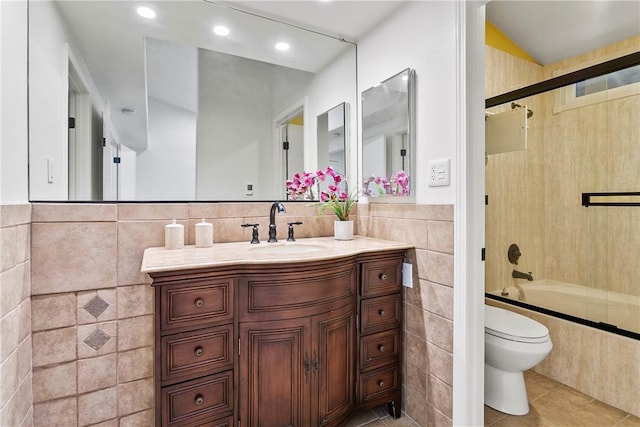 full bathroom featuring tile patterned floors, toilet, tile walls, vanity, and enclosed tub / shower combo