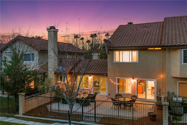 back house at dusk with a patio area