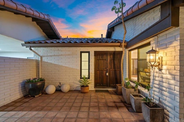 exterior entry at dusk featuring a patio area