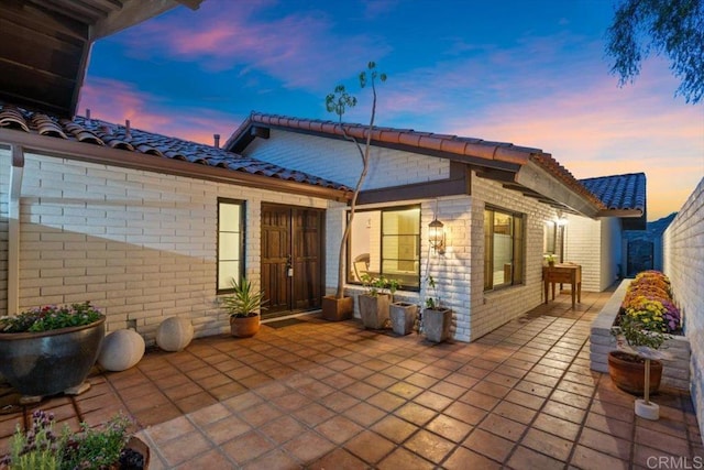 back house at dusk featuring a patio