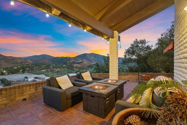 patio terrace at dusk featuring a mountain view and a fire pit