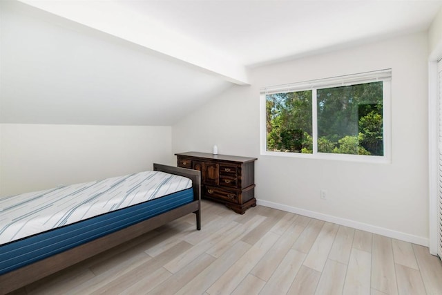 bedroom featuring lofted ceiling with beams and light hardwood / wood-style floors