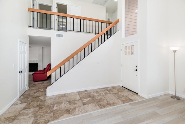 foyer entrance with a towering ceiling and a large fireplace