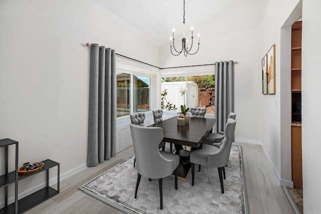 dining area featuring an inviting chandelier, vaulted ceiling, and light wood-type flooring