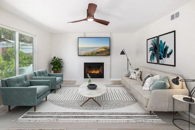 living room featuring a large fireplace and ceiling fan