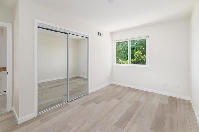 unfurnished bedroom featuring light hardwood / wood-style floors and a closet