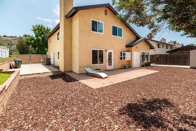 rear view of house with central AC and a patio