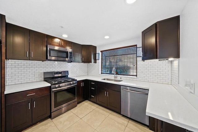 kitchen with light tile patterned floors, decorative backsplash, sink, dark brown cabinets, and stainless steel appliances