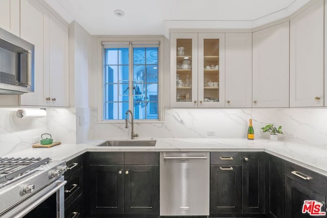 kitchen featuring decorative backsplash, sink, white cabinets, and stainless steel appliances