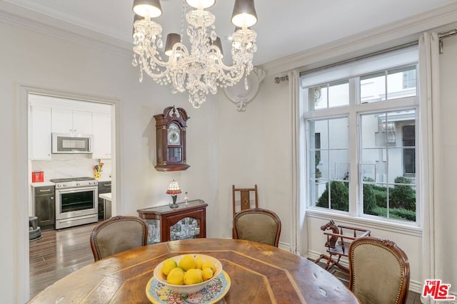 dining area with hardwood / wood-style floors, crown molding, and an inviting chandelier