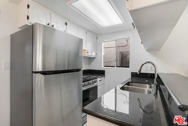 kitchen with sink, dark stone countertops, white cabinetry, and appliances with stainless steel finishes