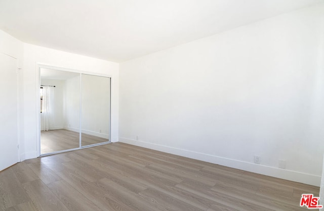 unfurnished bedroom featuring light wood-type flooring and a closet