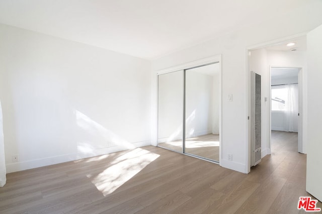 unfurnished bedroom with hardwood / wood-style floors and a closet