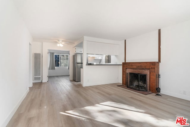 unfurnished living room featuring ceiling fan, light hardwood / wood-style flooring, and a fireplace