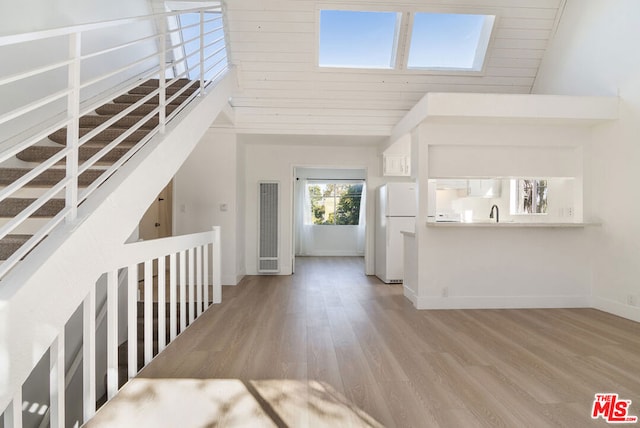 foyer entrance featuring sink, wooden ceiling, light hardwood / wood-style floors, and a high ceiling