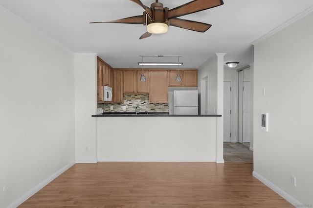 kitchen featuring decorative backsplash, white appliances, ceiling fan, and light wood-type flooring