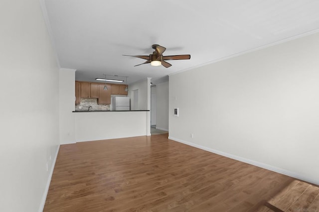 unfurnished living room featuring ceiling fan, rail lighting, wood-type flooring, and ornamental molding