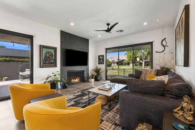 living room featuring a fireplace, ceiling fan, and light tile patterned flooring