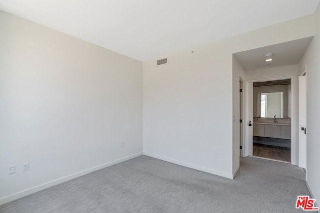 spare room featuring sink and light carpet