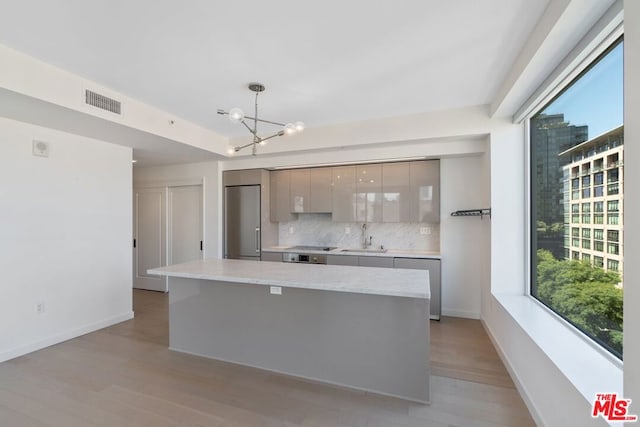 kitchen featuring tasteful backsplash, gray cabinetry, sink, pendant lighting, and stainless steel appliances