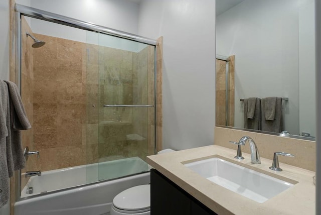 full bathroom with bath / shower combo with glass door, toilet, and vanity