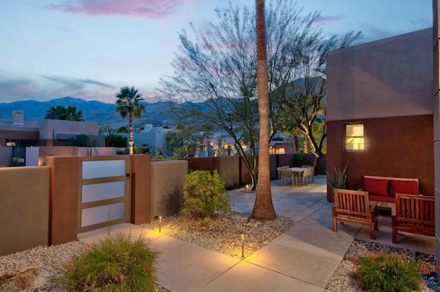 patio terrace at dusk featuring a mountain view and an outdoor hangout area