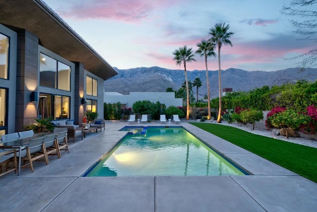 pool at dusk featuring a mountain view and a patio