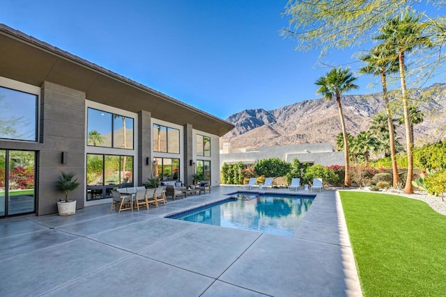 view of swimming pool with a lawn, a mountain view, and a patio area