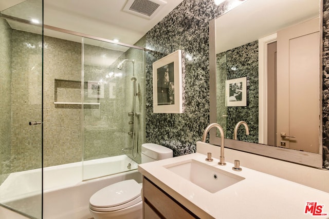 full bathroom with combined bath / shower with glass door, vanity, and toilet