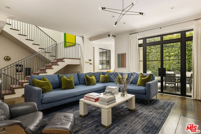 living room featuring dark wood-type flooring, ornamental molding, and a notable chandelier