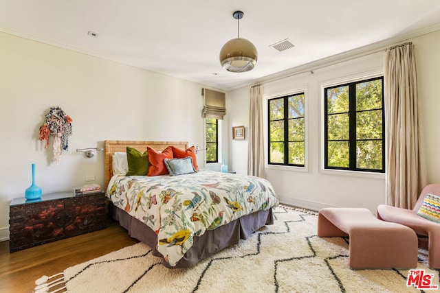 bedroom featuring ornamental molding and hardwood / wood-style floors