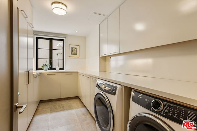 clothes washing area with cabinets and washer and clothes dryer