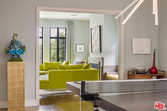 rec room with wood-type flooring and ornamental molding