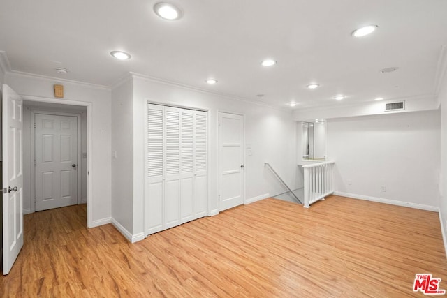 basement with ornamental molding and light hardwood / wood-style flooring