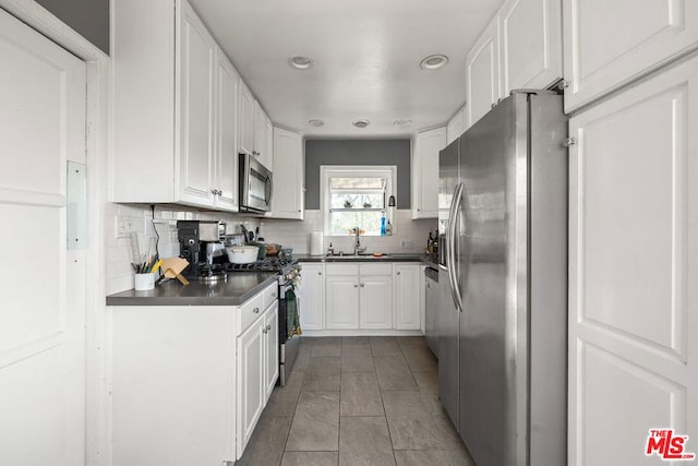 kitchen featuring light tile patterned floors, appliances with stainless steel finishes, sink, and white cabinets