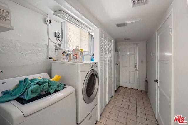 laundry area with light tile patterned floors and washer and clothes dryer