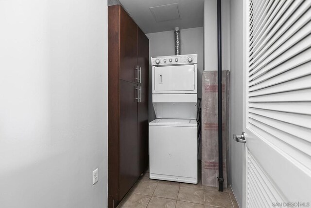 clothes washing area with stacked washer and clothes dryer and light tile patterned floors