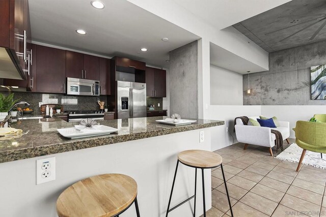 kitchen featuring sink, kitchen peninsula, stainless steel appliances, and dark stone counters