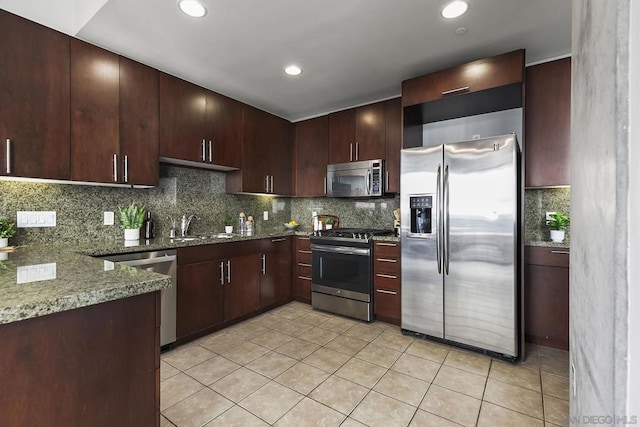 kitchen with light tile patterned flooring, dark stone counters, dark brown cabinetry, and appliances with stainless steel finishes