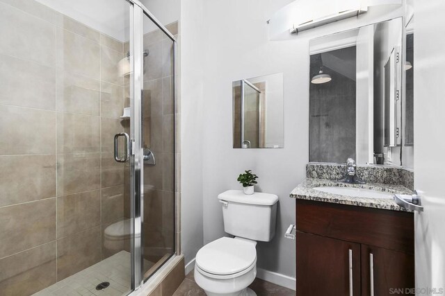 bathroom with vanity, a shower with shower door, and toilet