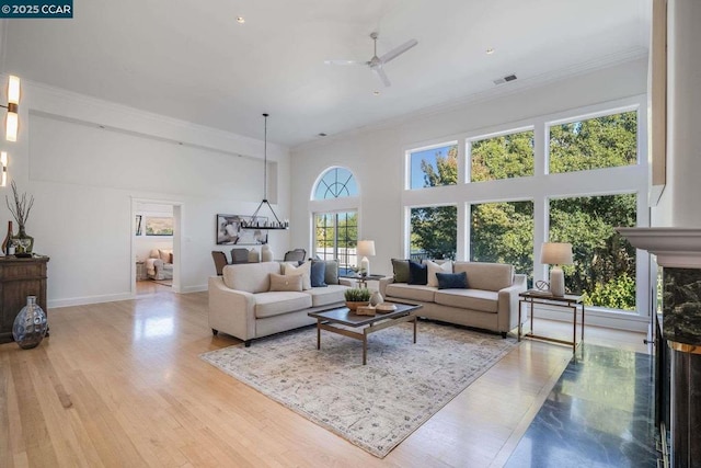 living room with ceiling fan, hardwood / wood-style floors, a high end fireplace, and crown molding