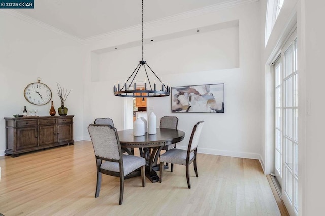 dining room with light wood-type flooring, ornamental molding, and a notable chandelier