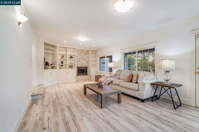 living room featuring light hardwood / wood-style floors, built in features, and a stone fireplace