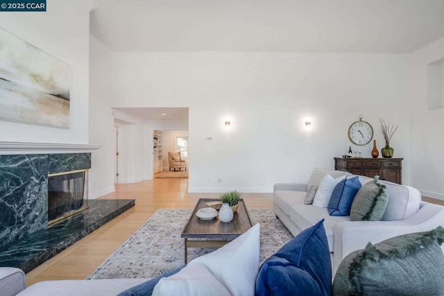 living room featuring light hardwood / wood-style flooring, ornamental molding, and a fireplace