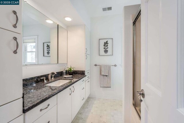 bathroom featuring shower / bath combination with glass door and vanity