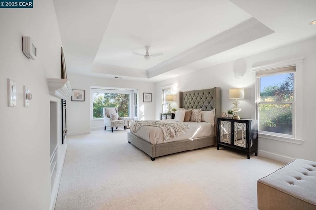 bedroom with light carpet, ceiling fan, a tray ceiling, and ornamental molding