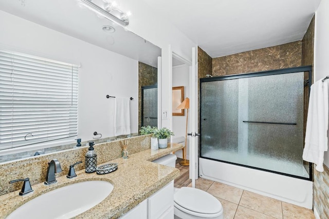 full bathroom with shower / bath combination with glass door, vanity, toilet, and tile patterned flooring